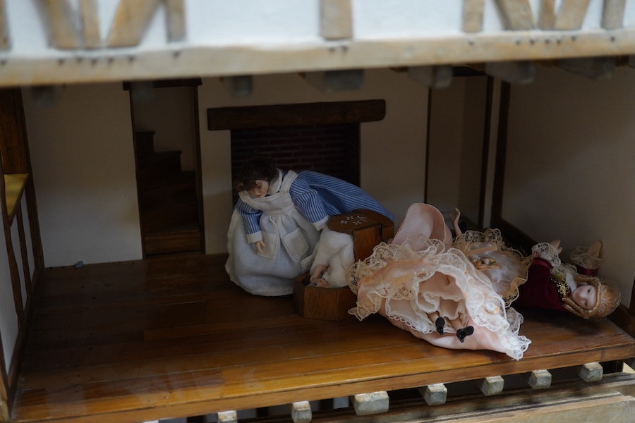 A modern doll’s house in the form of an oak framed Tudor house on three floors, with a shop on the ground floor, removable front panels on each floor and one side of the roof, with internal detailing and a good selection